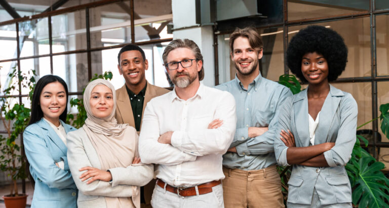 Sechs diverse Fachleute stehen aufrecht in einem modernen Büro, lächelnd und selbstbewusst.